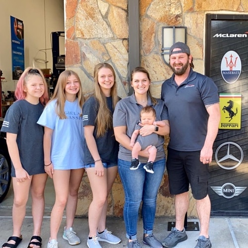 EurAuto Shop Plano Tx, pictured in front of EurAuto Shop front office door is owner Michael Gallini and his wife, three teenage daughters and infant son
