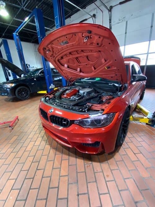 EurAuto Shop in Plano Tx, bmw repair and service on a red BMW sedan with hood open to perform vehicle maintenance services to it