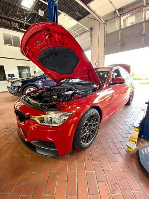 EurAuto Shop in Plano Tx, bmw repair and service on a red BMW sedan with hood open to perform vehicle maintenance services to it