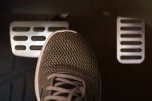 gray tennis shoe going to press on brake pedal in car