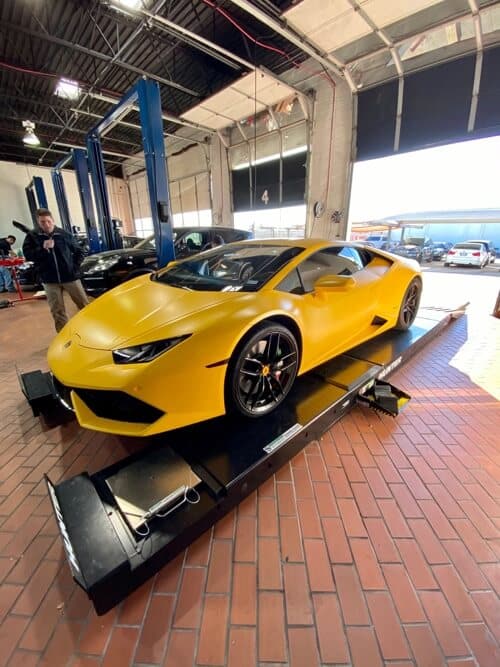 yellow lamborghini repair in plano tx on alignment machine lift in shop bay