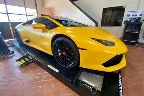 EurAuto Shop in Plano Tx, exotic auto repair and service on a yellow lamborghini that is on lift inside bay area of shop ready for service