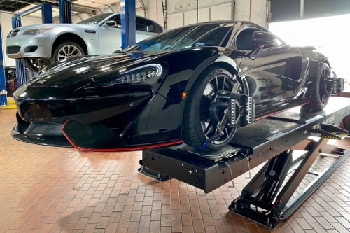 EurAuto Shop in Plano, Tx. black exotic sports car on car lift hooked to their state of the art alignment machine in shop bay