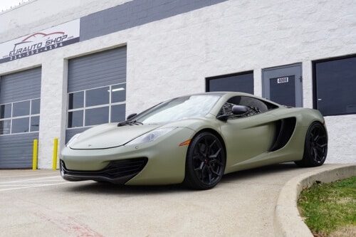 Fixing a McLaren MP4 - 12C Water Pump Leak with EurAuto Shop in Plano, Tx. Image of army green mclaren pictured outside EurAuto shop office door