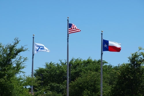 Richardson Tx, American and Texas flags flying on poles; EurAuto Shop in Plano Tx.
