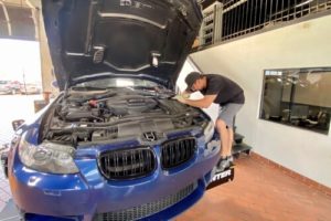 Prepping Your M Series BMW For More Power and Torque with EurAuto Shop in Plano, Tx. image of mechanic working on blue BMW M Series engine in shop bay