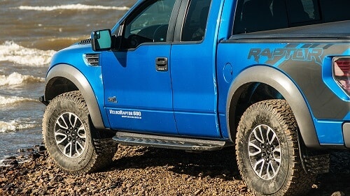 First Gen Ford Raptor Performance Upgrades by EurAuto Shop in Plano, TX. Image of a blue Ford F150 Raptor SUV driving on dirt road.