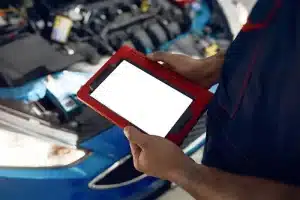 How To Find The Best Diesel Car Repair in Plano, TX? | EurAuto Shop in Plano, TX. Close up view of blank digital tablet screen in a mechanic’s hands and an open car hood background.