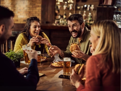Plano, TX best places to eat near EurAuto Shop. Image of 2 happy couples having conversations eating burgers and drinking beers.