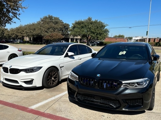 BMW A/C Repair Services near me with EurAuto Shop in Plano, TX. Image of two BMWs, one white and one black, parked side by side after undergoing BMW Air Conditioning Service.