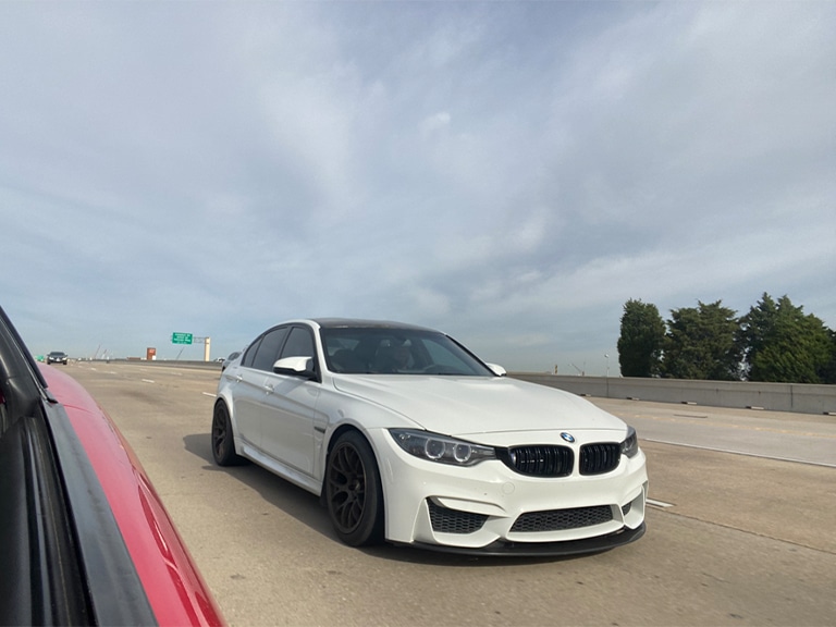 Common issues with the BMW 320i E90 in Plano, TX with EurAuto Shop, bmw repair shop mechanics. Image of White BMW 320i E90 driving down Texas highway and side view of red car that took the picture.