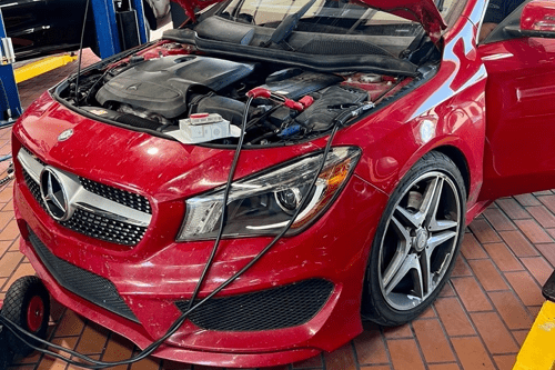 Common Cold Weather Issues for European Cars in 2024 with EurAuto Shop in Plano, TX. Image of newer red mercedes car with hood open and battery cables connected to the battery for testing.