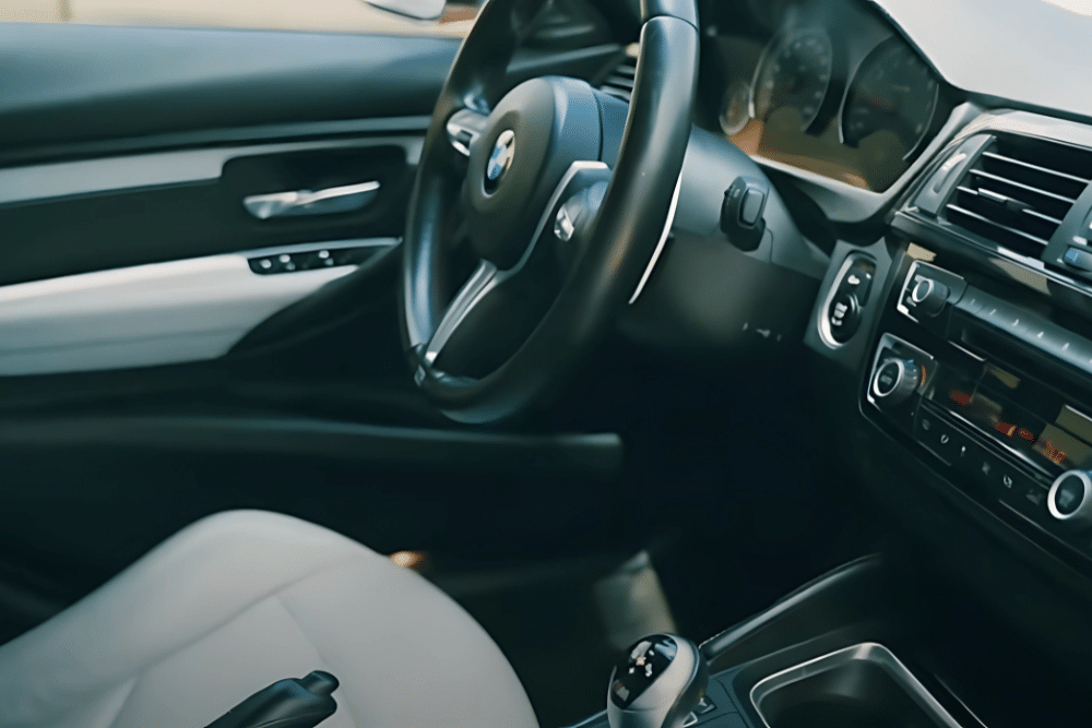 BMW warning lights, european auto repair in Plano, TX at EurAuto Shop. BMW interior featuring a black leather steering wheel, digital dashboard, and a modern center console with climate controls and an infotainment system.