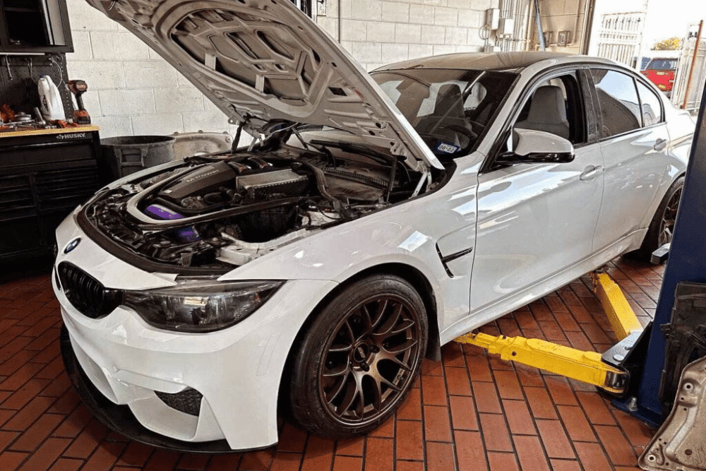 car care in Plano, TX by EurAuto Shop -- a car with an open hood in an auto shop getting routine maintenance service